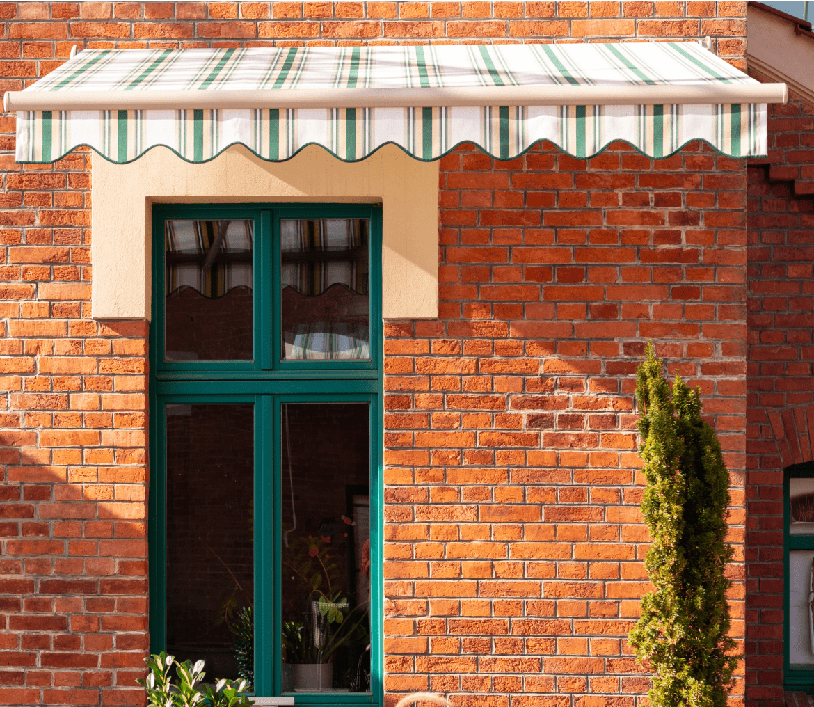 Brick wall with window and striped awning.