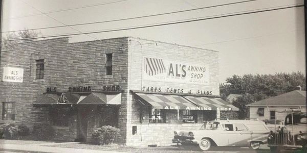 Black and white photo of ALS Grocery Store with a vintage car parked outside.